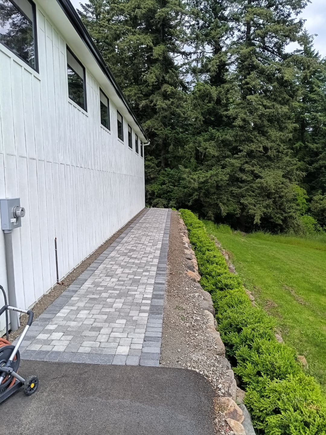 picture of a newly installed paver walkway on a side of a home with gray textured pavers